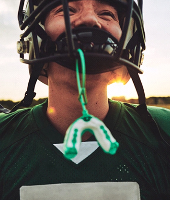 A male football player wearing sports equipment and a custom mouthguard