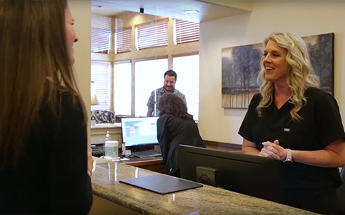 mother holding daughter and smiling at front desk worker