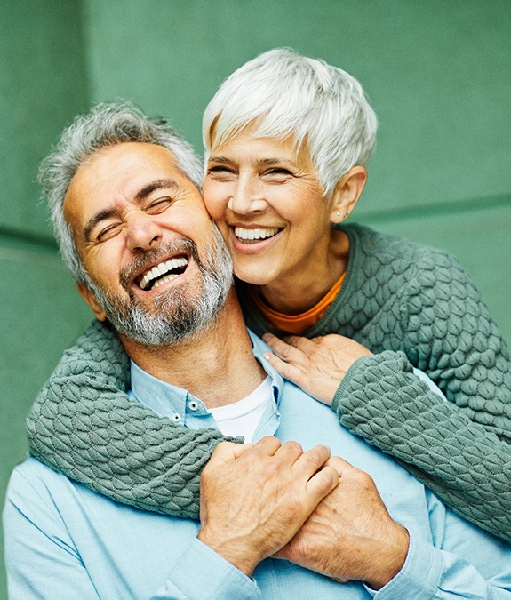 Senior woman hugging senior man from behind