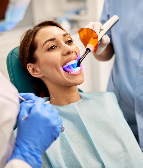 Woman in dental chair having filling hardened with curing light